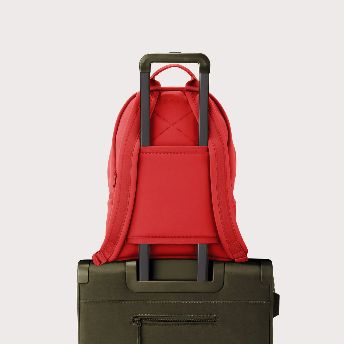 Dagne Dover Medium Dakota Backpack in a fiery, saturated red leaning toward orange on luggage, showing the luggage sleeve.