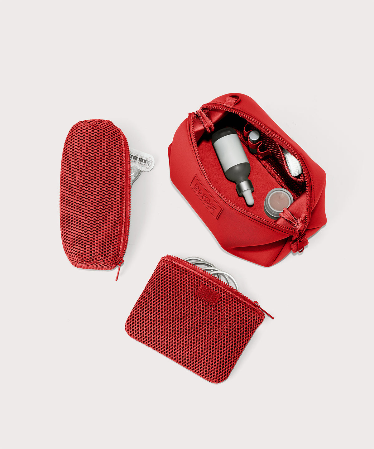 Dagne Dover Large Hunter Toiletry Bag in a fiery, saturated red leaning toward orange unzipped and seen from above with the removable air mesh pouch alongside it.