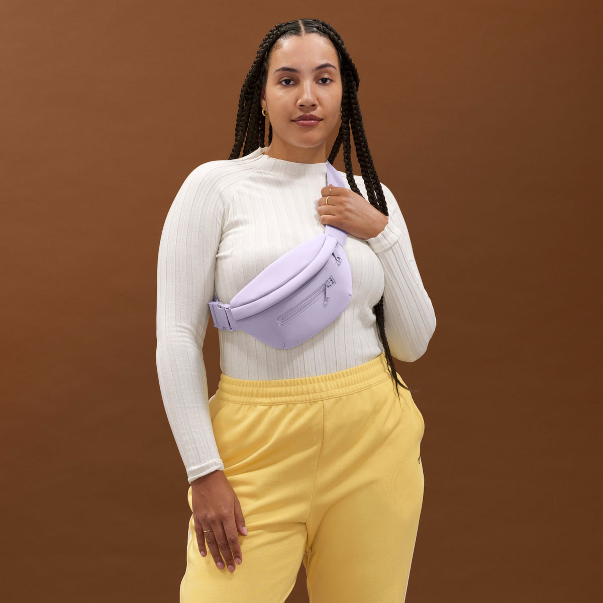 NoPDP A woman wearing the Ace Fanny Pack in light purple as a crossbody bag. Model: Logan is 5'11"